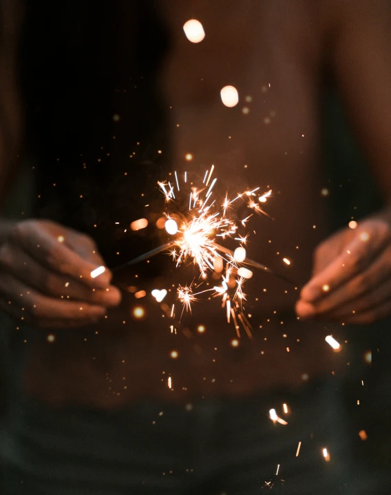 a woman is holding up a small sparkler