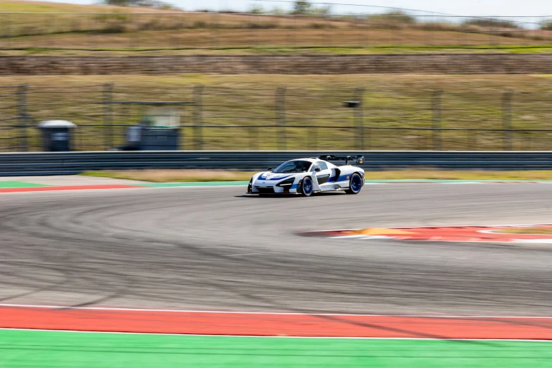 the car races on the racetrack next to a tall fence