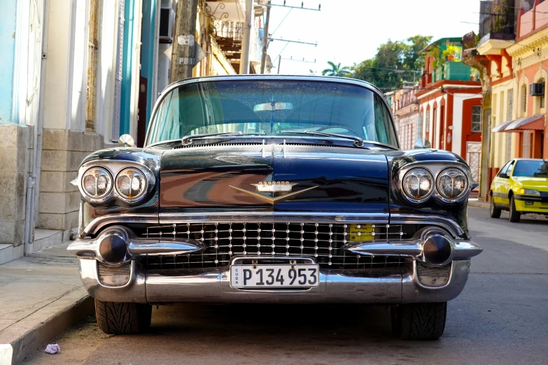 an old model car is sitting on a city street