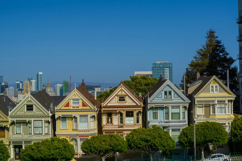 the row houses are painted different colors in front of the city skyline