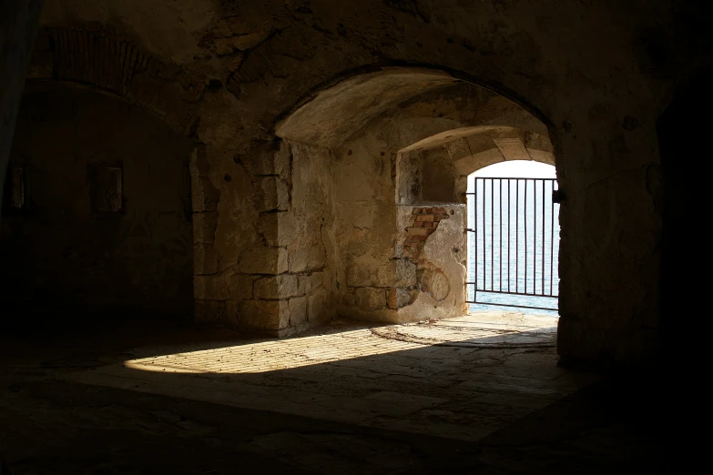 a dark hallway with the sunlight coming through the gate