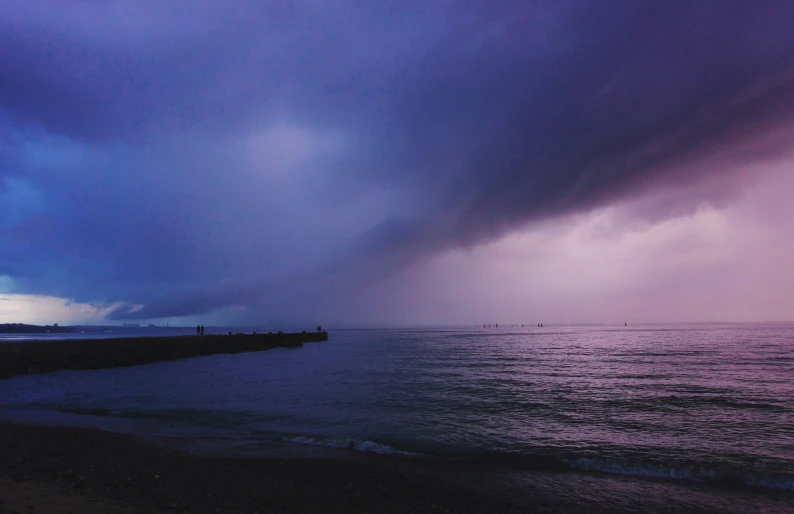 the sky is filled with heavy rain over the ocean