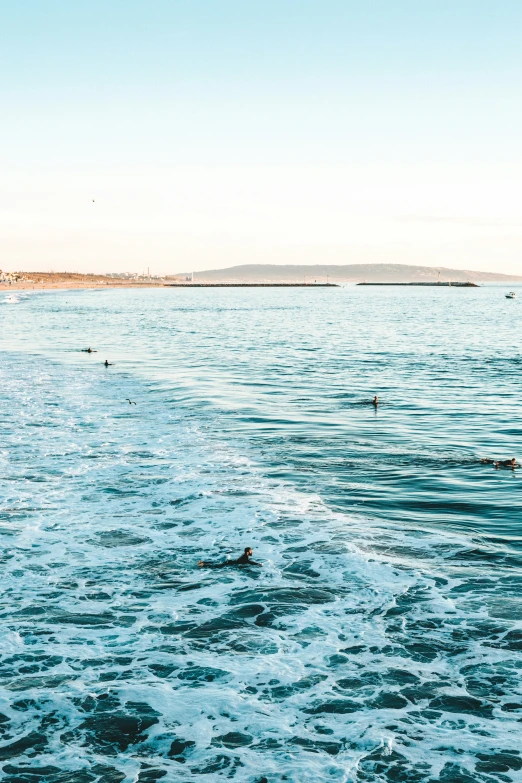 several people swimming and swimming in the water at the beach