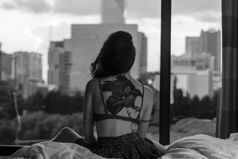 a young woman with tattoos looking out the window