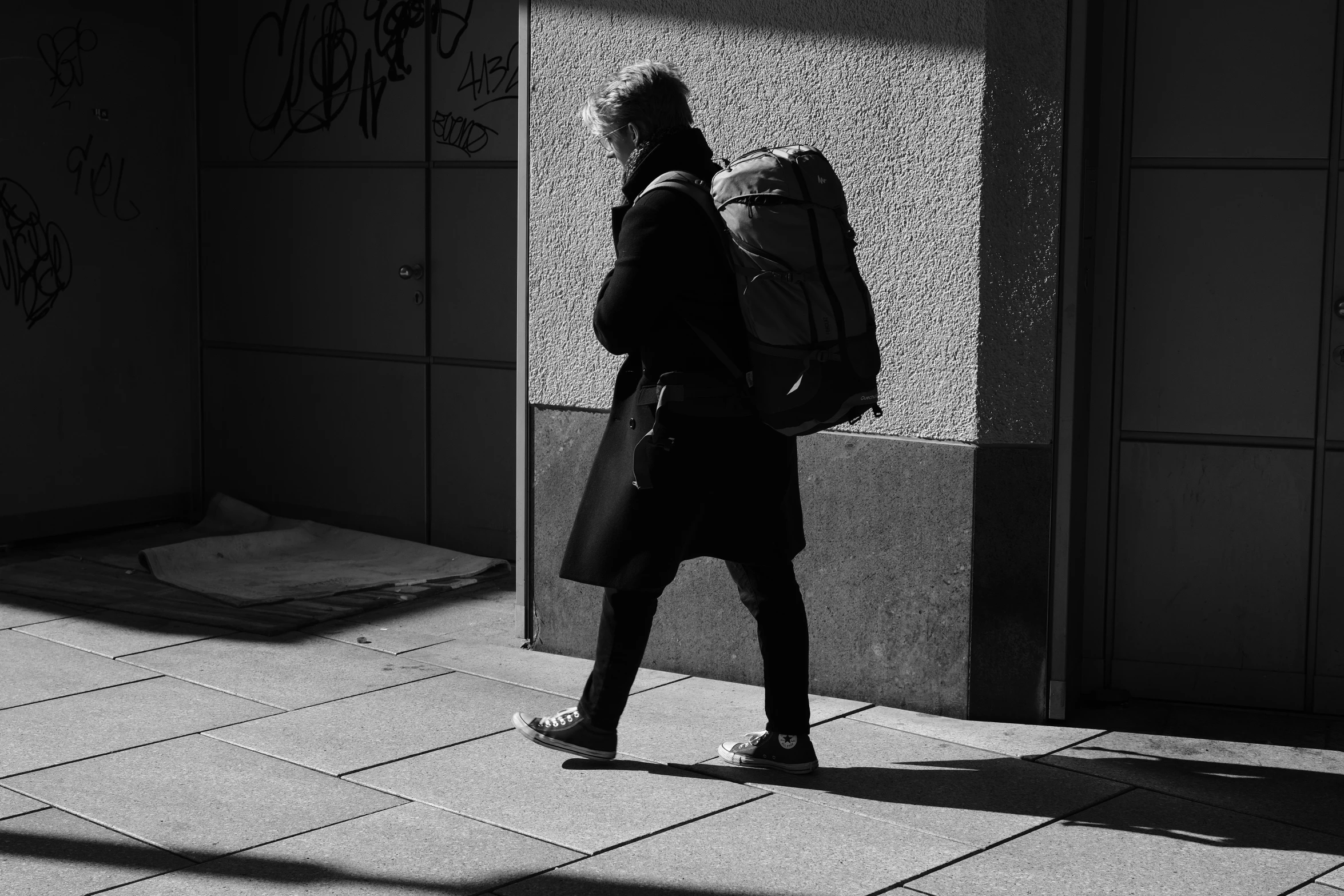 a man with a backpack walking down a sidewalk