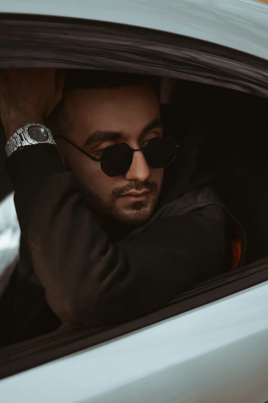 a man in sunglasses looking out a car window