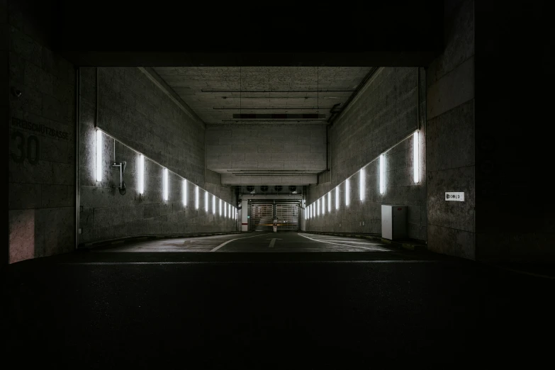 a dimly lit tunnel under a road with lights