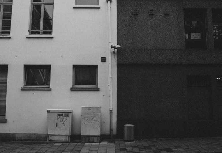 two trash cans outside a building with many windows