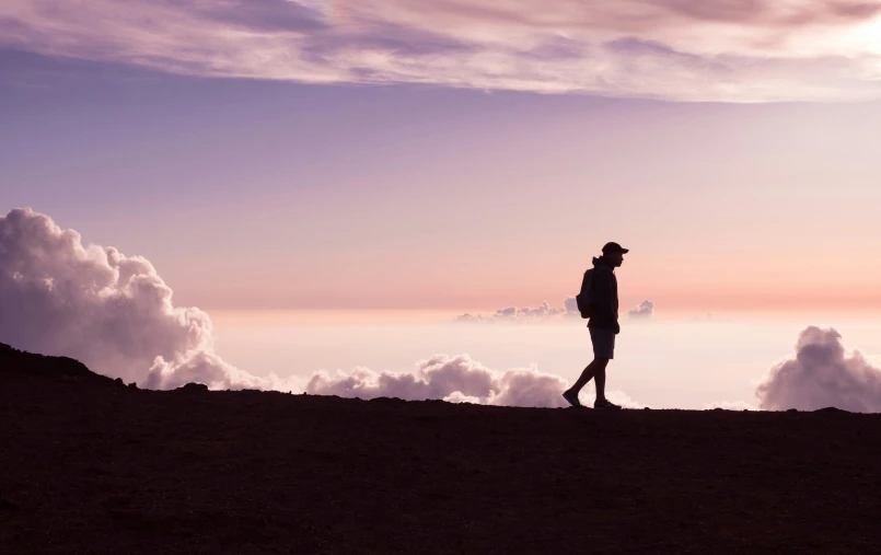 a man in a hat and coat on top of a mountain