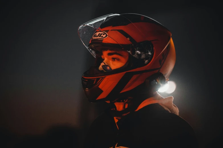 a man wearing a helmet and red jacket with light around it