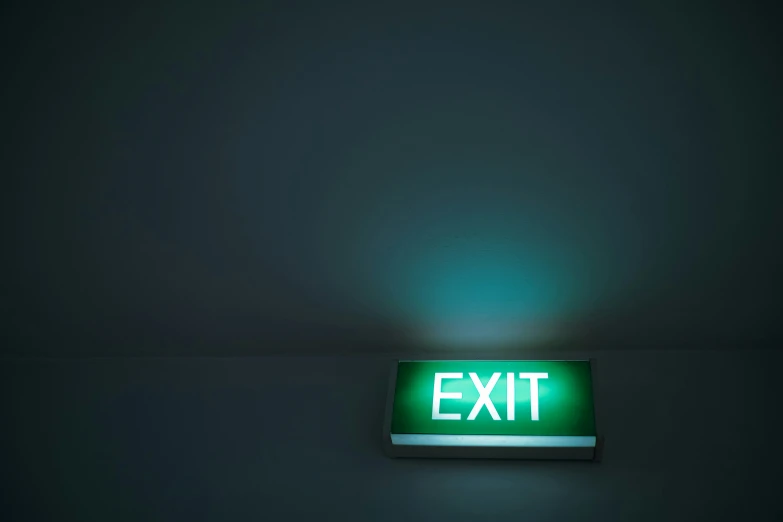 a green light on a black wall and the word exit lit up