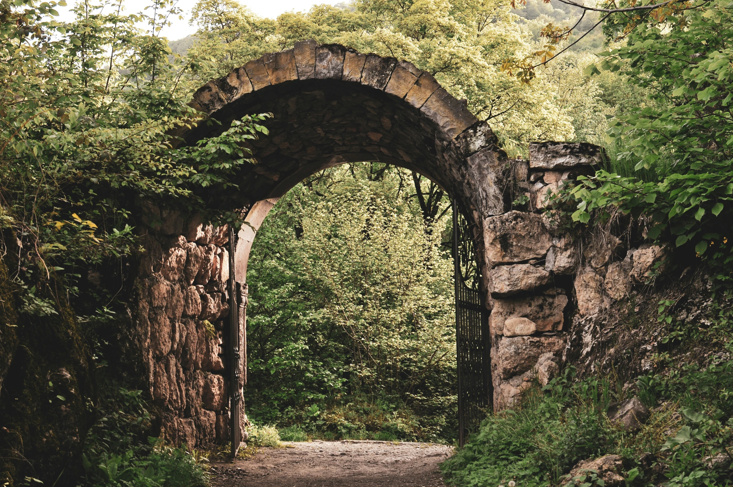 there is an arched stone arch near the road