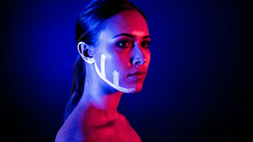 a person with an odd face lit by a neon light