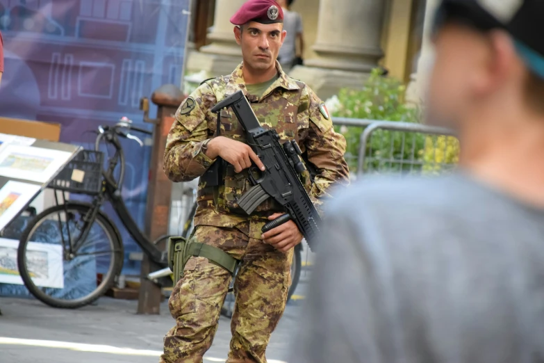 a man in uniform holding a rifle with another man in the background