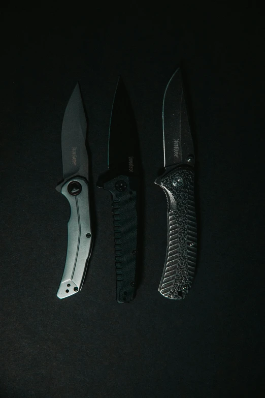 three knives with dark background on top of them