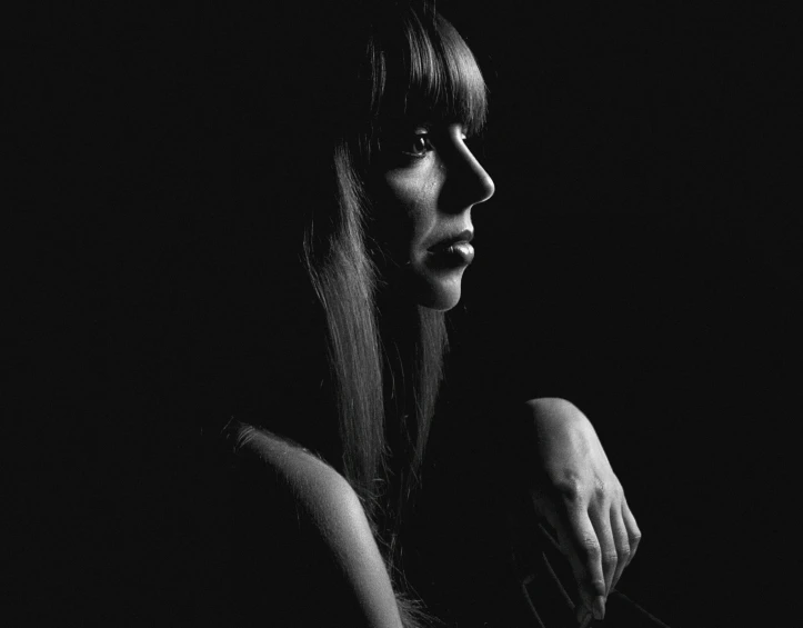 a woman sitting in the dark wearing a black shirt