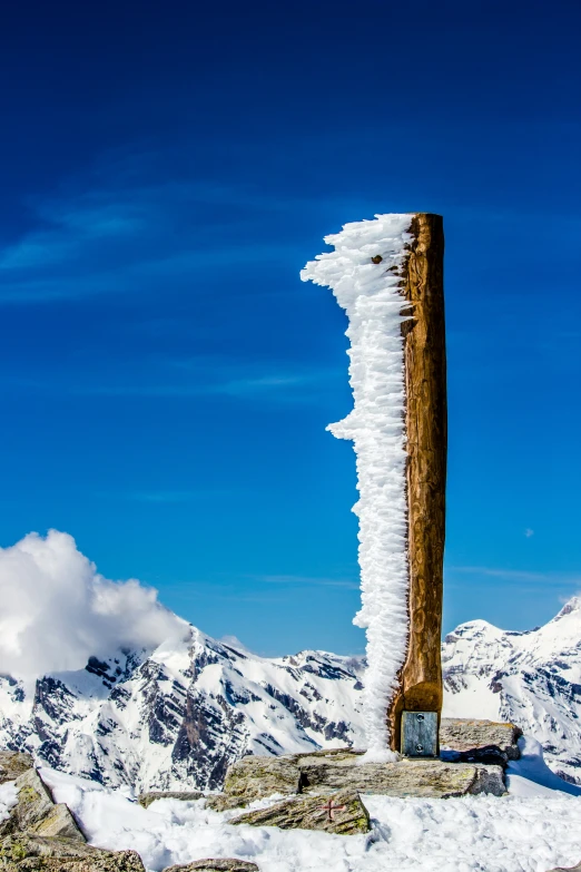 an ice covered pole stands in the snow