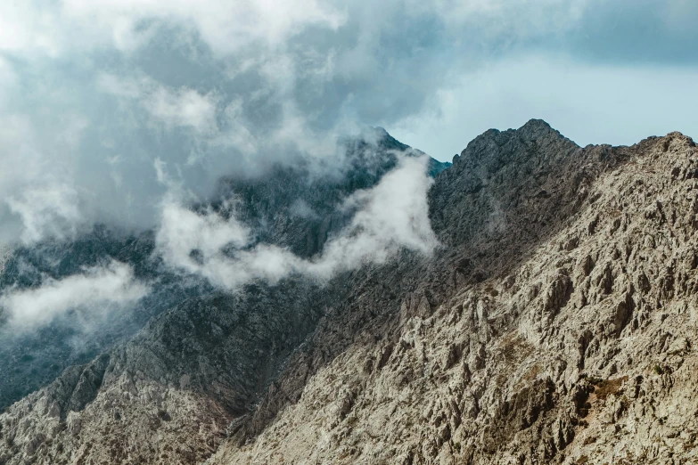 a view of clouds rolling over a mountain peak