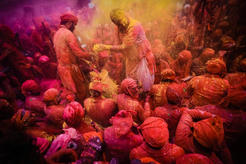 a crowd of people standing around each other covered in colored powder