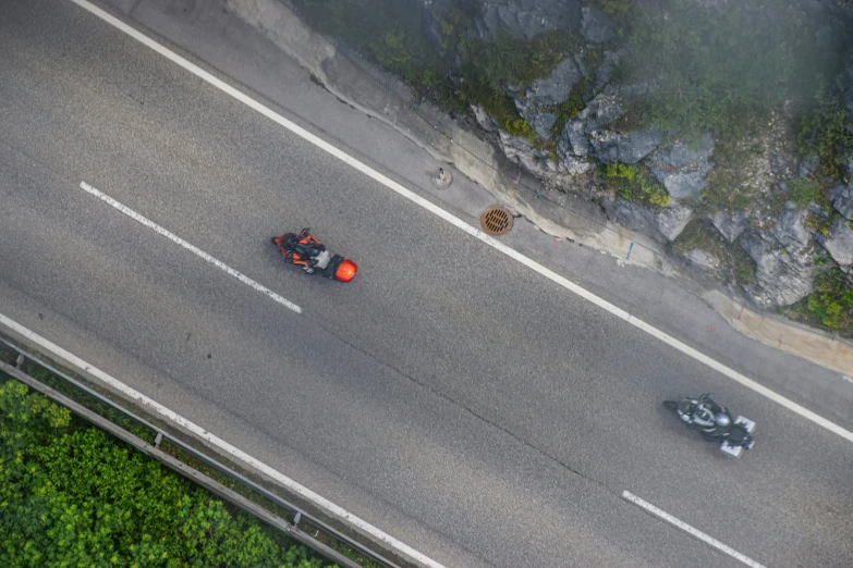 two motorbikes driving on road with tall cliffs