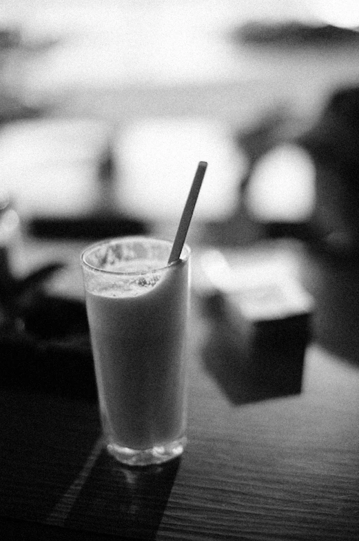 a glass with soing sitting on top of a wooden table