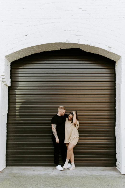 man and woman standing by a garage door holding hands