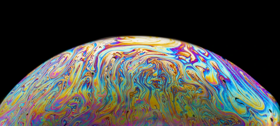 a large multicolored piece of liquid on black background