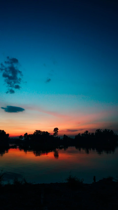 the blue sky and dark water are illuminated by dusk