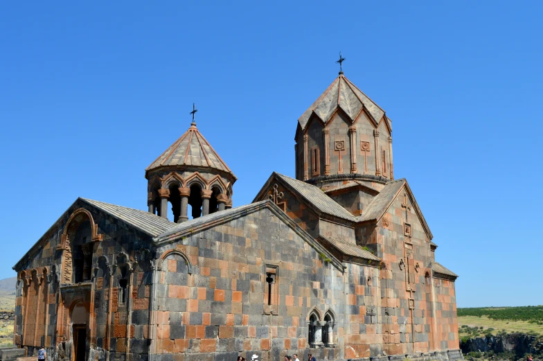 a stone church with two steeples and people walking past it