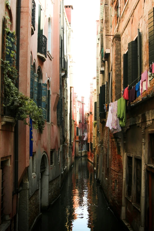 a canal with clothes on a clothes line in between two buildings