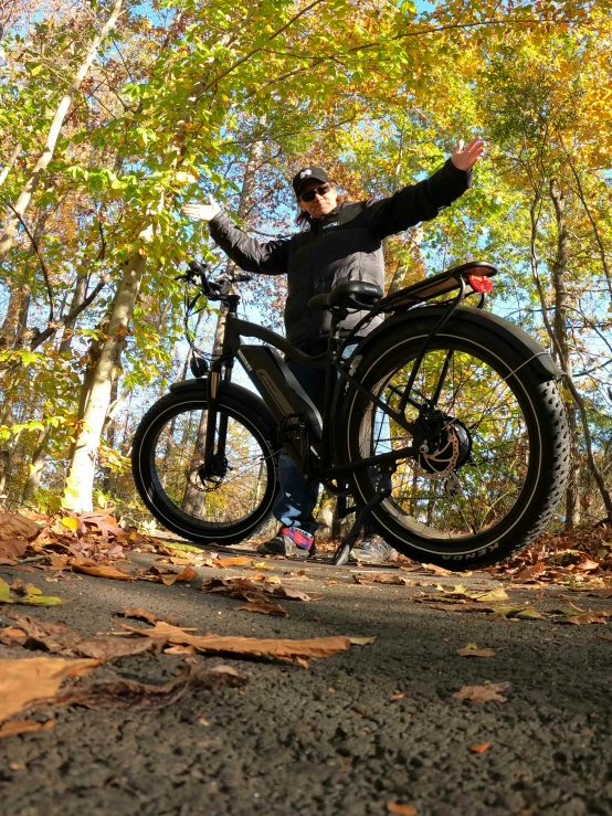 a man riding his bike in the woods with arms outstretched