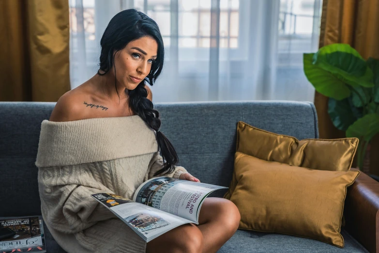 a woman sitting on a couch with a book in her hand