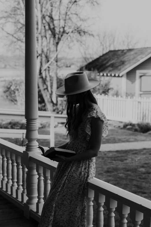 a woman wearing a straw hat standing on a porch