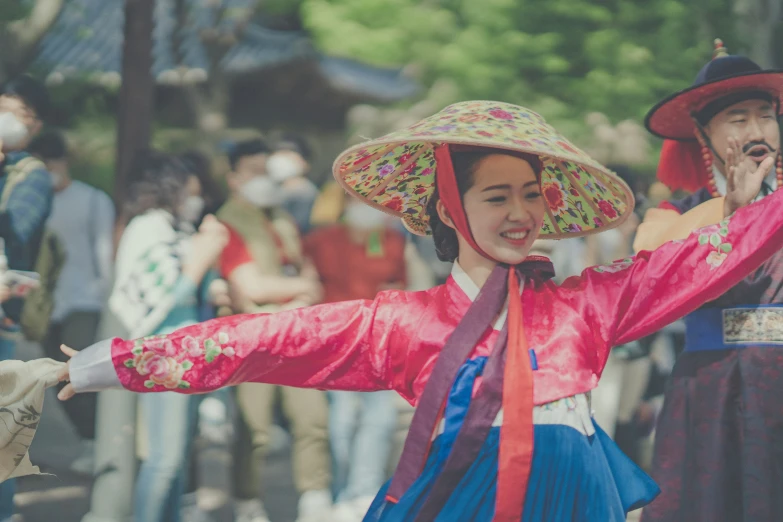 two women dressed in traditional attire and hats are dancing