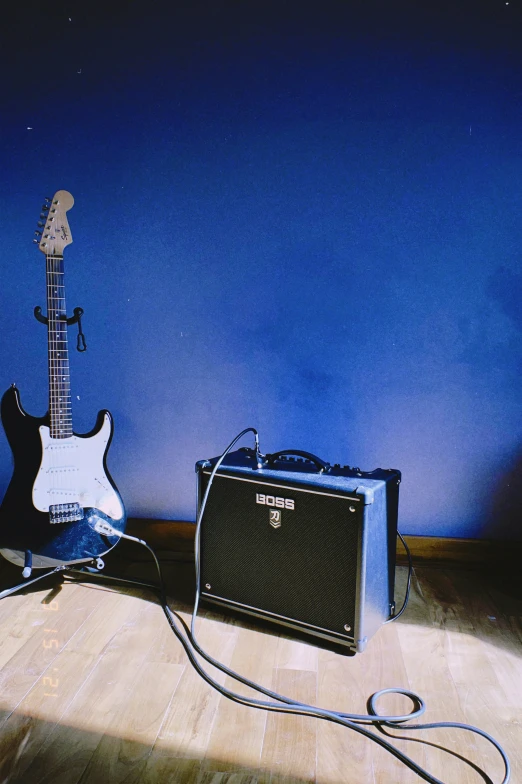 two guitars and a guitar amplifier on a hard wood floor