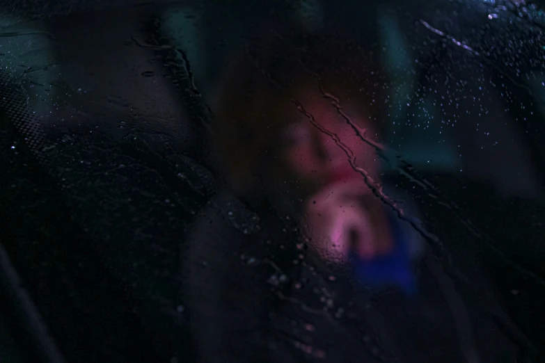 a person is seen through a glass and raindrops