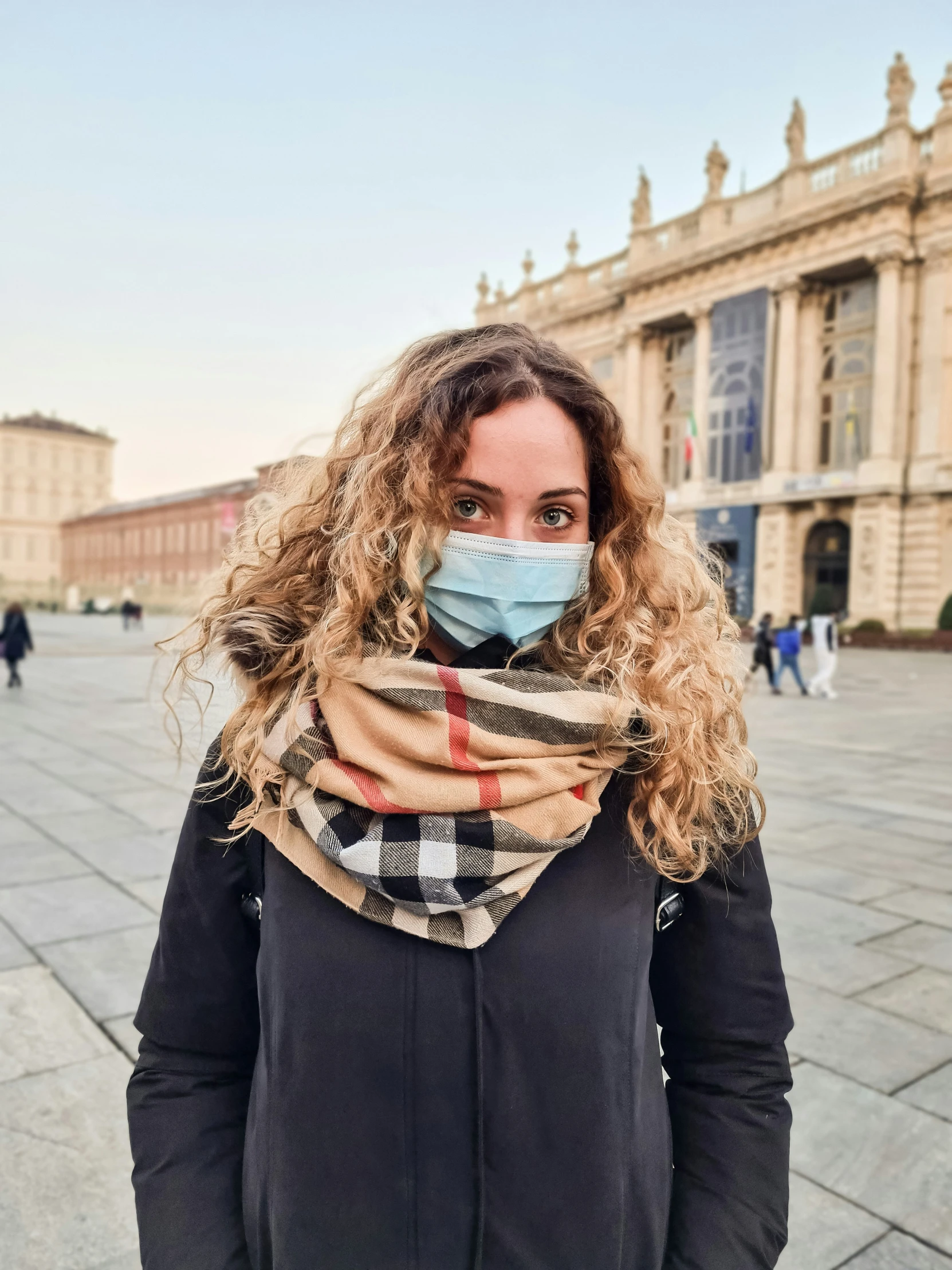 a woman with a face mask in front of a building