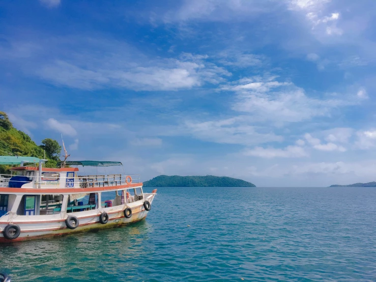 a tourist boat floating on the water with a mountain in the background