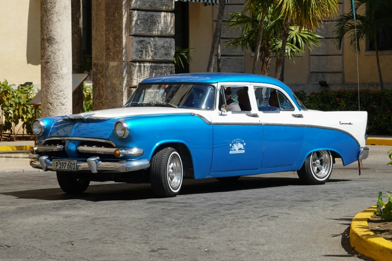 a classic blue and white car parked on a street