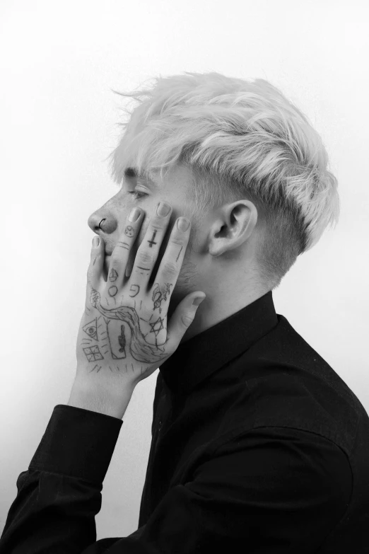 a man with a tattooed hand covering his face