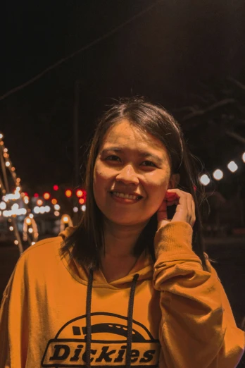 young asian lady wearing yellow sweatshirt talking on phone