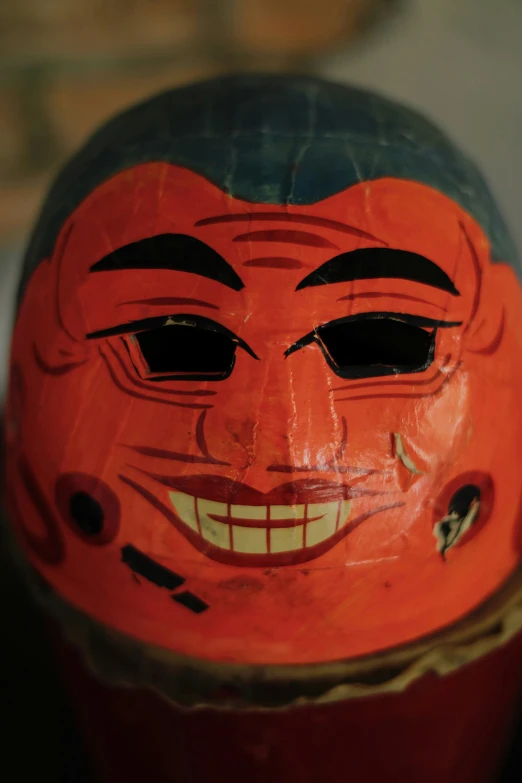 an orange mask is wearing a smile with black eyes