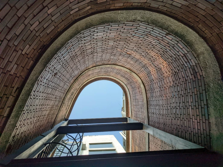 a narrow brick archway with two steel hand rails