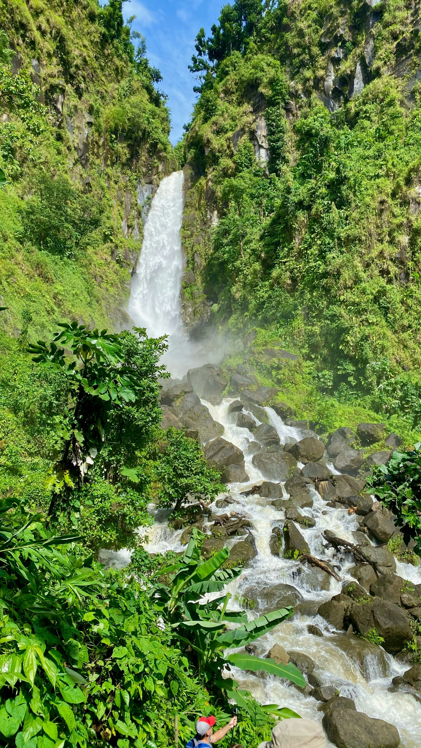 a group of people on bikes riding on the road near a waterfall