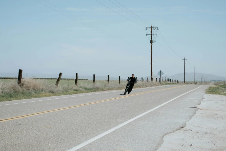 a motorcycle is traveling down a road during the day