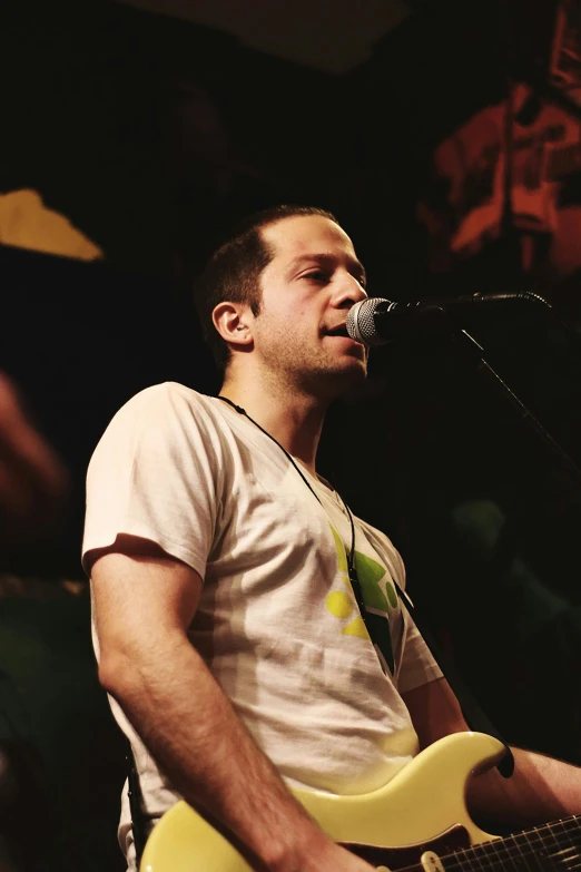 a man on stage singing into microphone and playing an electric guitar