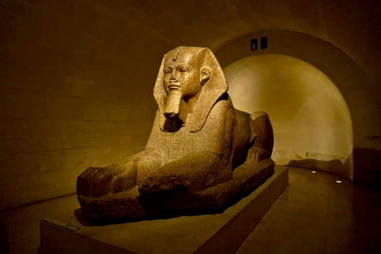 a small statue of an egyptian sitting in a museum