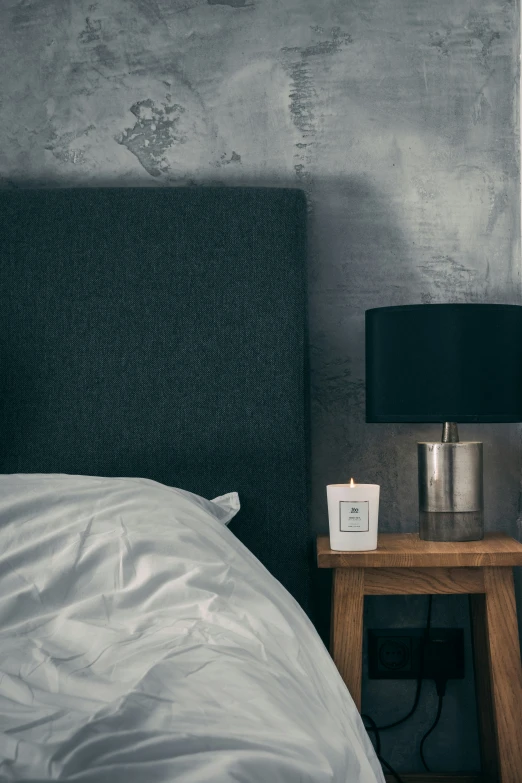 a bedside table with a candle in a dark bedroom