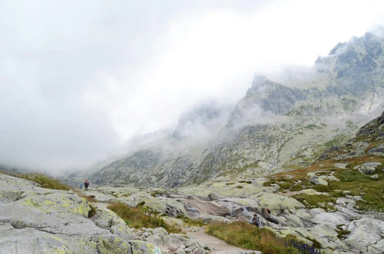 a couple hikers on a mountain side with low clouds