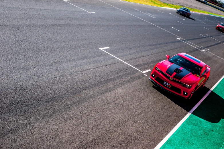 a red car driving on a track in front of other cars